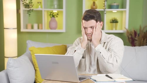 While working from the laptop, the young man's mood drops and sighs in front of what he sees.