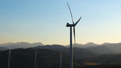 Wind Turbines Spinning at Sunset in Hilly Landscape