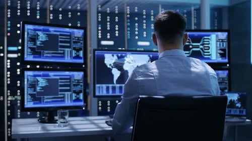 Vista posterior del controlador/operador técnico trabajando en su estación de trabajo con varias pantallas. Posts