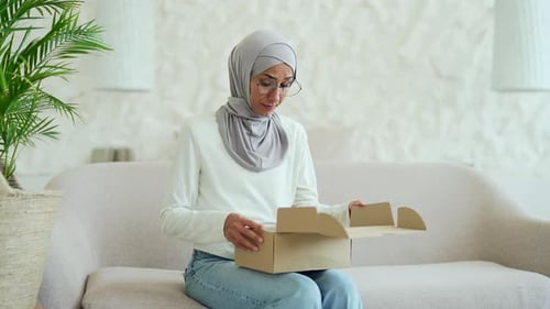Young Muslim woman in hijab received a parcel dissatisfied with shopping in online internet store