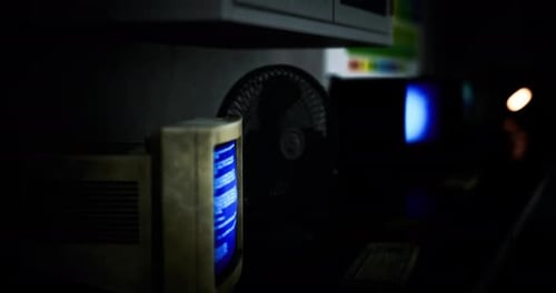 Vintage Computer Setup Illuminated in a Dimly Lit Room with Retro Decor