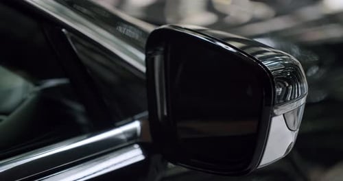 Closeup on Side Rear View Mirror of Black Shiny Car