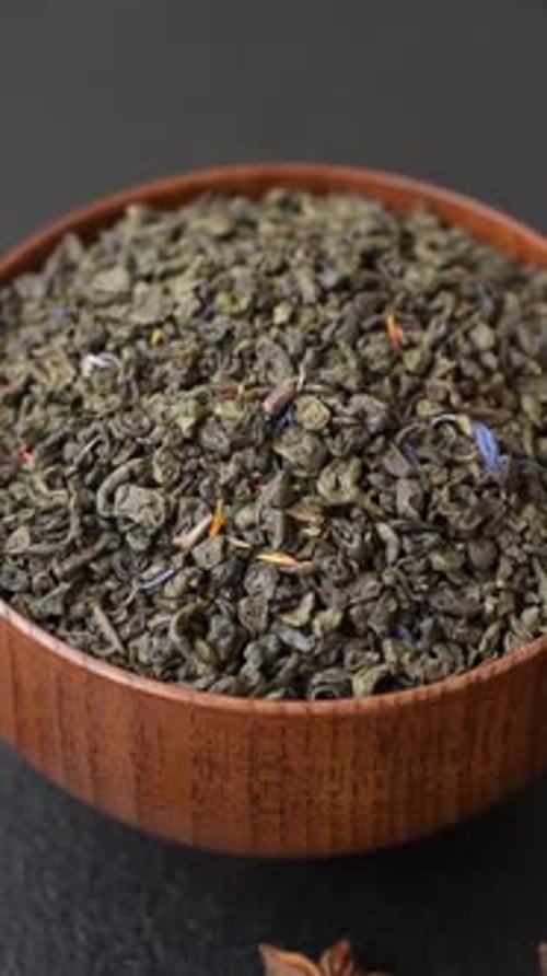 Granules of dried organic Chinese green tea with herbal additives. Dry green tea