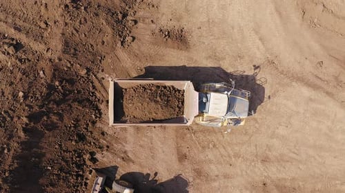 Excavator loading soil onto a Truck, Aerial view.