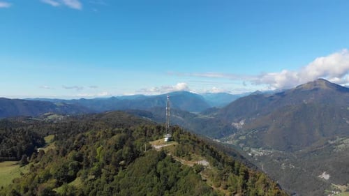 Communications antenna on summit of vast mountain peak valley lush green hillside aerial orbit righ