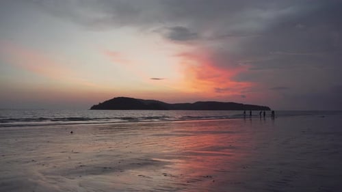Kleiner Junge rennt bei Sonnenuntergang an einem Sandstrand entlang