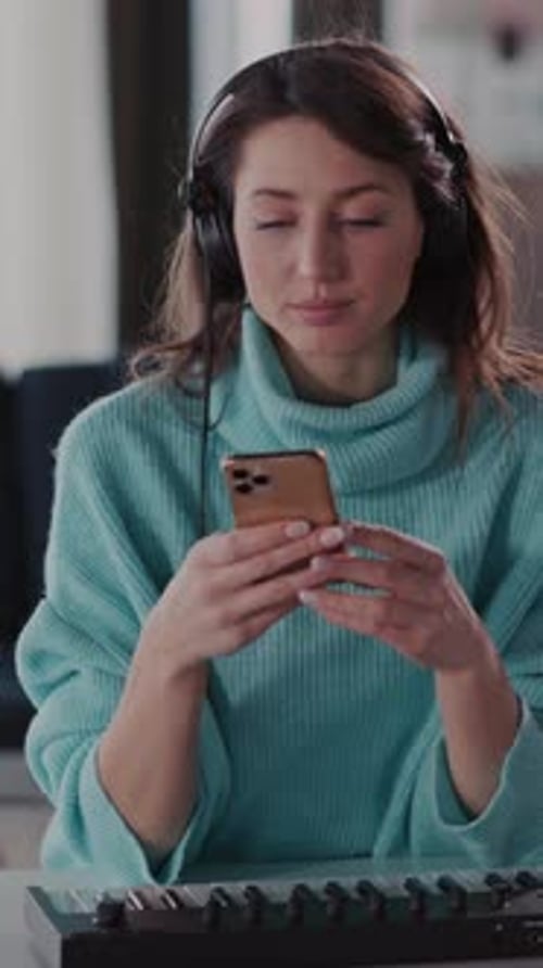 A Focused Woman Works with a Computer and Headphones Multitasking