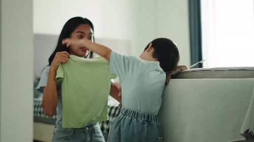Young Woman Folding Clothes with Child in Home