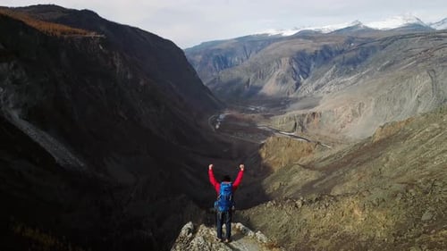 Hiker Celebrating Reaching Mountain Peak with Arms Raised