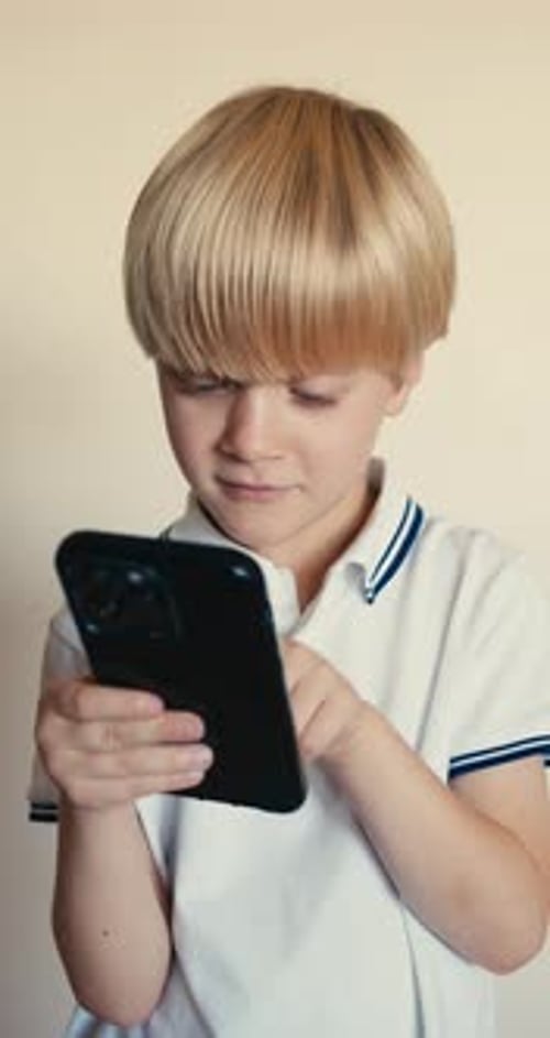 Focused Boy Uses Smartphone at Home