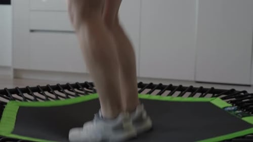 Person Exercising Jumping on Trampoline Indoors