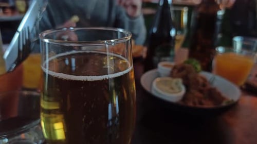 Eine Nahaufnahme eines Glases Apfelwein, während die Leute im Hintergrund Essen von Tellern holen.