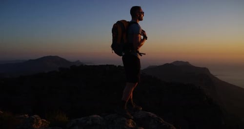 Man, hiking and training for adventure, mountain top and peak, sunset and backpack