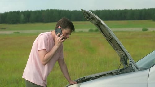 Man Talking on Phone Next To Broken Down Car