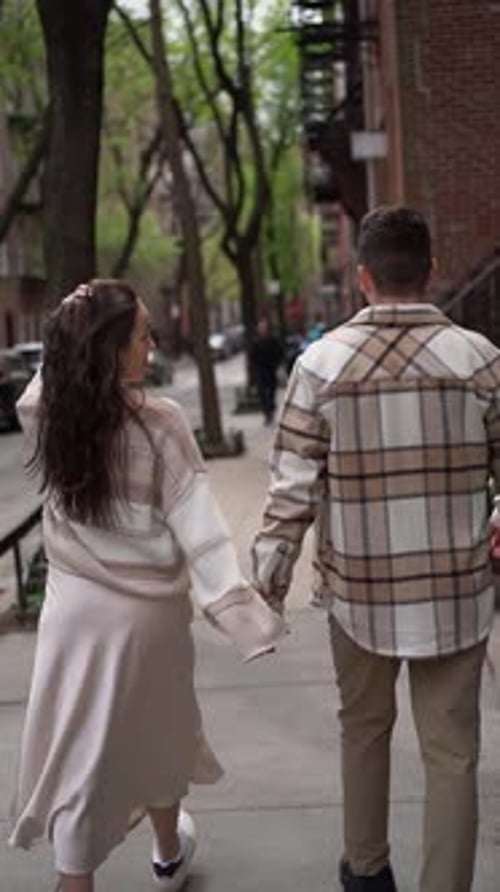 A Couple Walks Holding Hands on a City Street Sharing a Romantic Moment