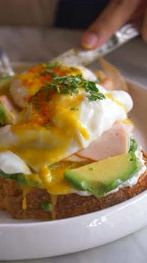 Close Up of a Dish with Eggs Ham and Avocado on a Toast