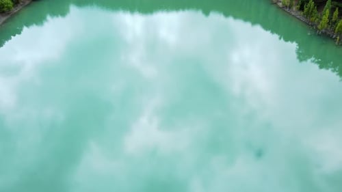 Aerial View Over a Turquoise Lake with a Reflection of the Passing Clouds