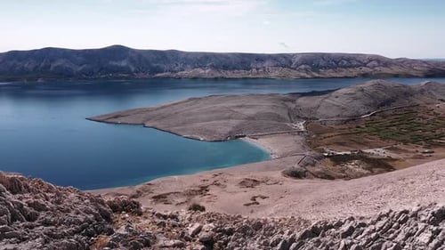 Drone fly through rocky mountains, revealing the coast and sea.