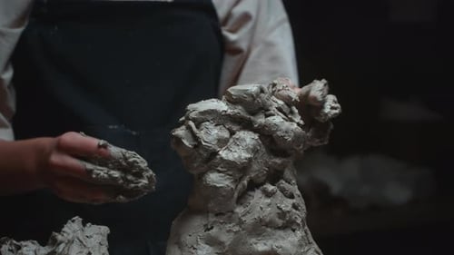 Artist Sculpting Clay in Dark Studio
