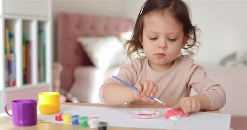 Young Child Painting with Paintbrush at Table