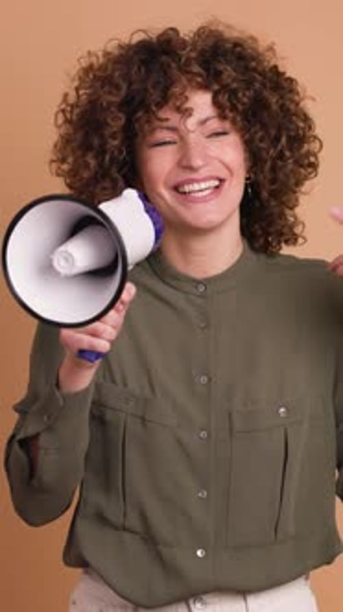 Excited Young Woman Screaming on Loudspeaker in Beige Studio Vertical Orientation