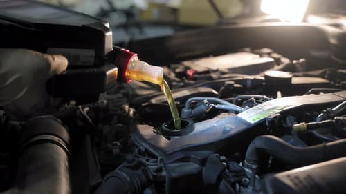 The Closeup View of a Mechanic Changing the Car Motor Oil in a Repair Shop During the Car Inspection