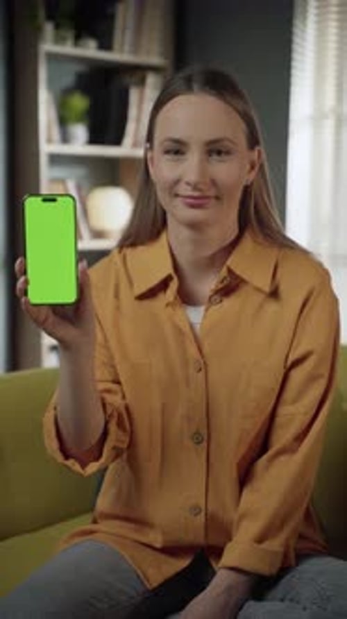 Smiling Woman Presenting Smartphone with Green Screen at Home