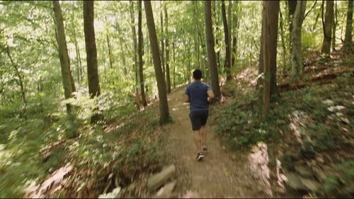 Young male running through forest