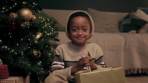 Smiling Child with Candy Canes by Christmas Tree