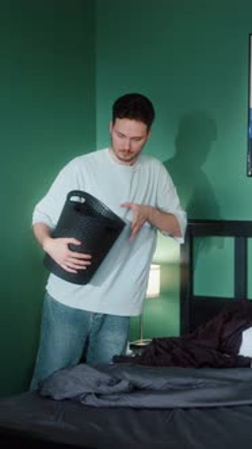 Man Throwing Garbage Into Bin in Bedroom
