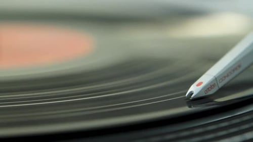 A close-up of a turntable needle playing a vinyl record, capturing the grooves in detail