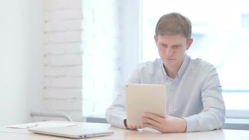 Man Using Tablet at Desk in Bright Office
