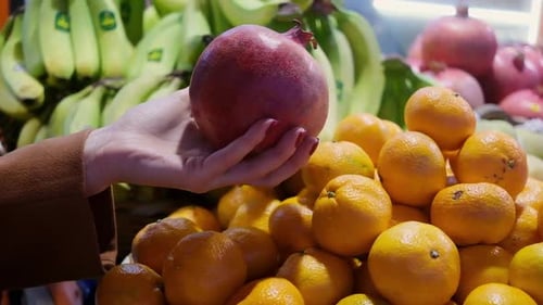 Woman Hand Choosing Pomegranate at Fruit Vegetable Shelf in Grocery Store Healthy Food Nutrition