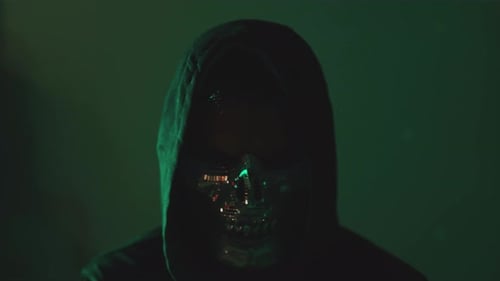 Hacker encapuzado: ciberatacante com máscara e capuz assistindo câmera