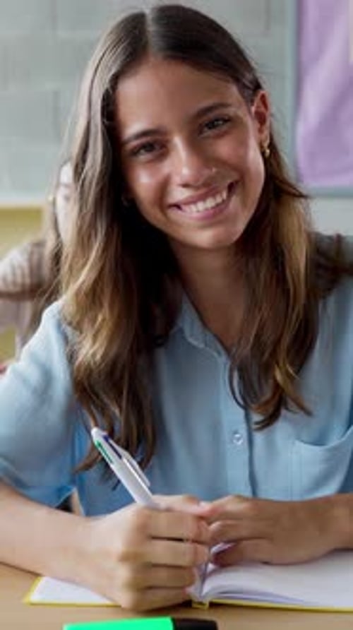 Teen Smiling at Desk in Classroom