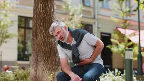 Mature Man Experiencing Stomach Ache in City Park