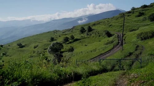 A Rural Road Meanders Through Lush Green Hills Under a Blue Sky Winding Country Road Through Vibrant