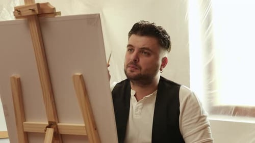 Male Artist Paints on a Canvas in Studio