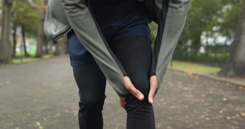 Man Holding Sore Knee in a Park