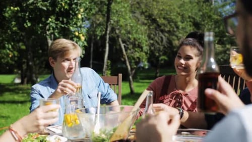 Leisure, Holidays, Eating, People And Food Concept - Happy Friends Having Dinner At Summer Garden...