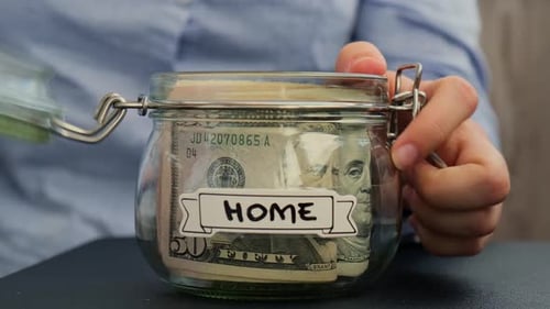 Person Saving Cash Money in Jar for Home