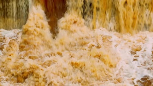 Aerial view captures muddy floodwaters churning turbulently.