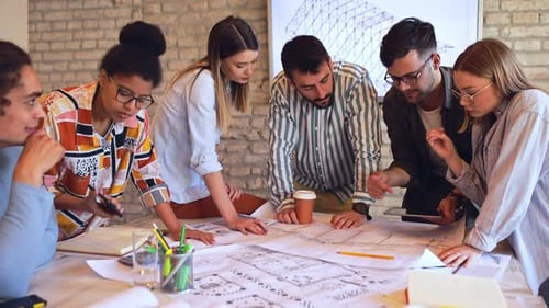 Group of young business people discussing architectural designs in office.