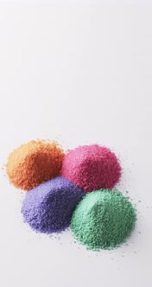 Vertical video of close up of multi coloured sand grains and copy space on white background