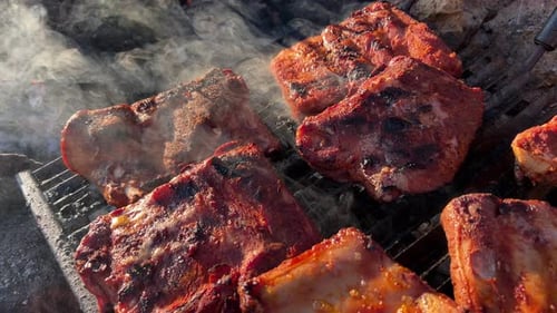 Cooking juicy bbq pork ribs on an outdoor fire grill with smoke and ashes, delicious food, 4K static