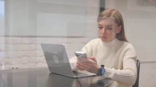 Woman Using Laptop and Smartphone in Modern Office