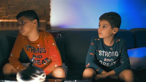 Two Boys Sitting on Couch Watching Something