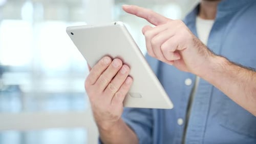 Close up of male hands holding digital tablet at workplace in modern business office. Adult business