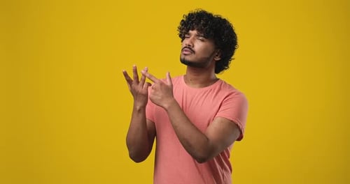 Pensive Indian Man Counting on Fingers Standing Over Brown Studio Background