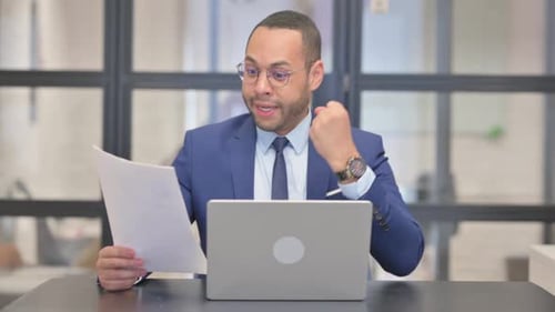 Enthusiastic Young Adult Working on Laptop in Office